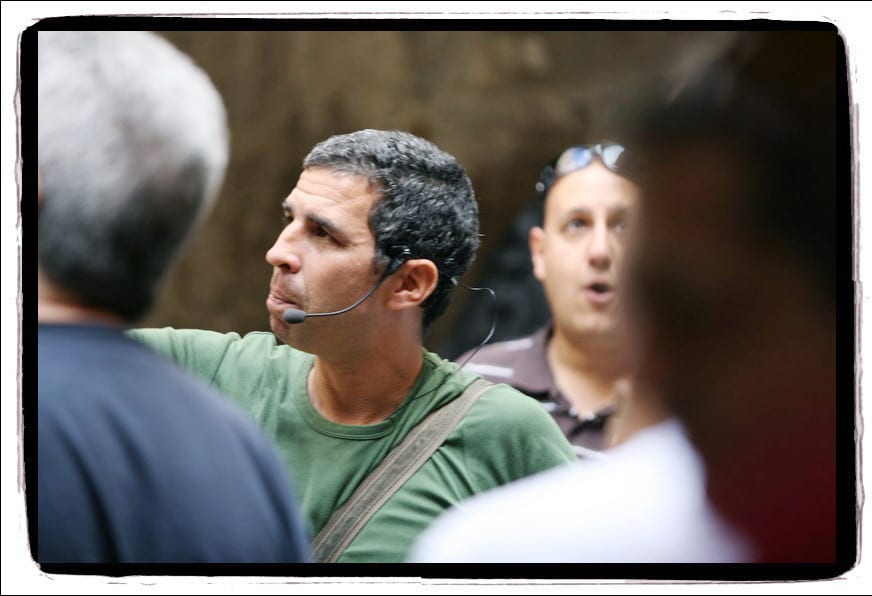 מדריך עם מיקרופון ראש מסביר לקבוצת משתתפים ברחוב בתל אביב